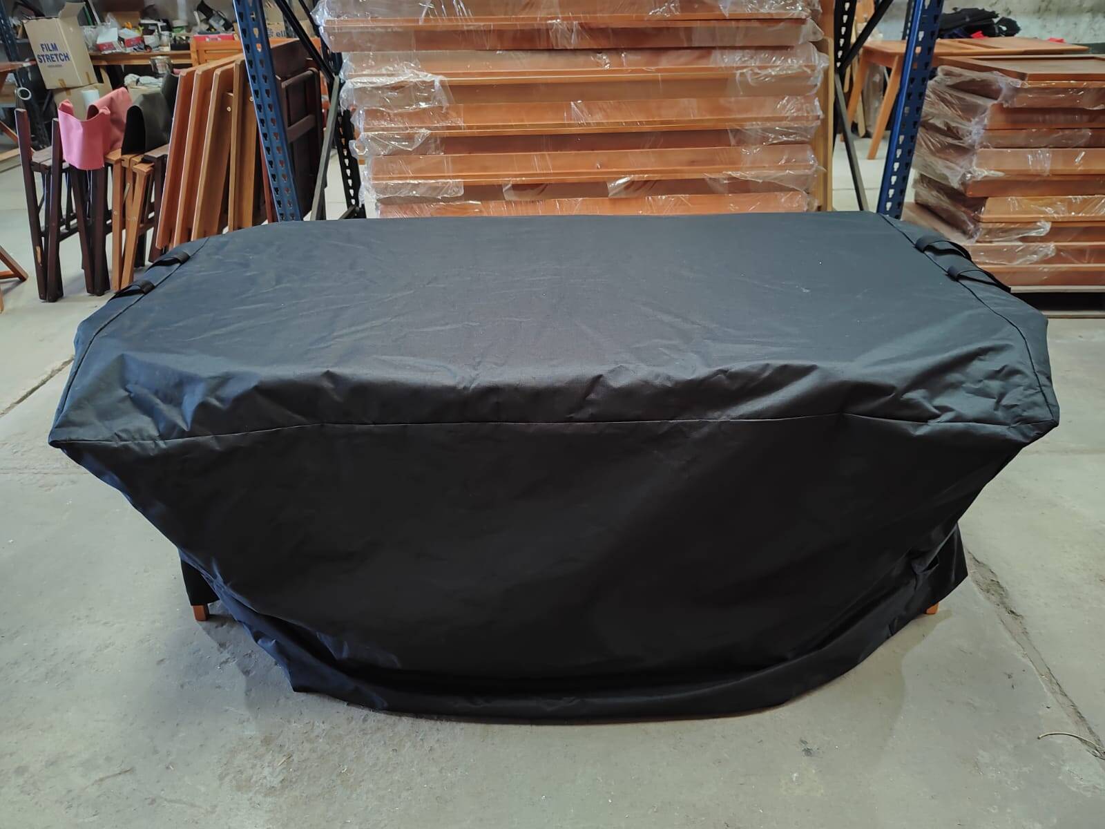 WhatsApp Image 2026-07-23 at 33205 PM 1 | Fabrica de muebles | Forestry | Muebles de Exterior Large rectangular object covered with a black protective cloth on a concrete floor in a workshop or warehouse.